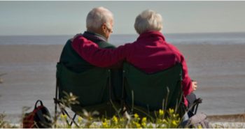 elderly couple sat together looking out to sea